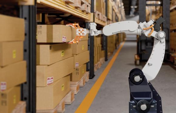 A robot picking up a box in a warehouse of a business.