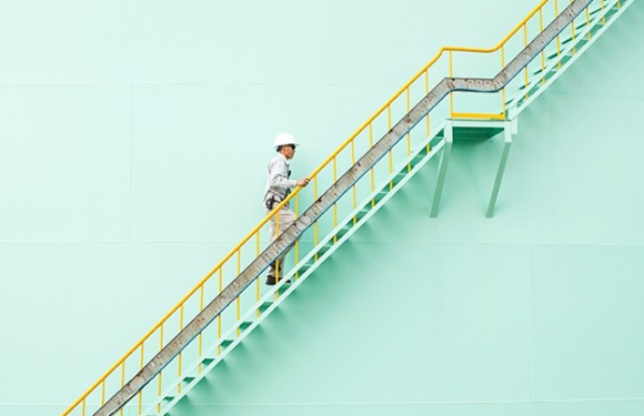A man with a helmet climbing up a flight of stairs to new heights